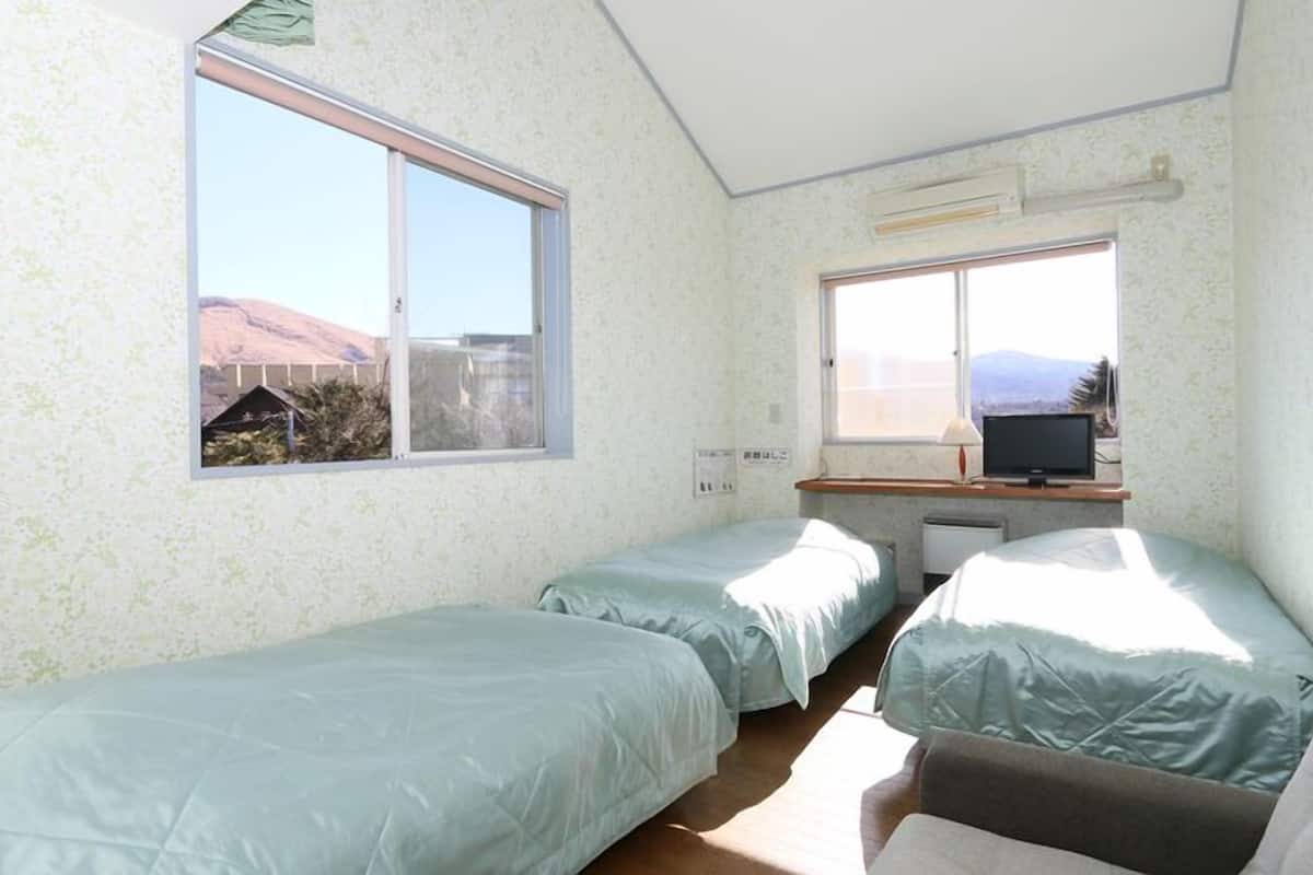 Ein Zimmer mit zwei Betten, einem Schreibtisch mit Computer und einem Fenster mit Bergblick.