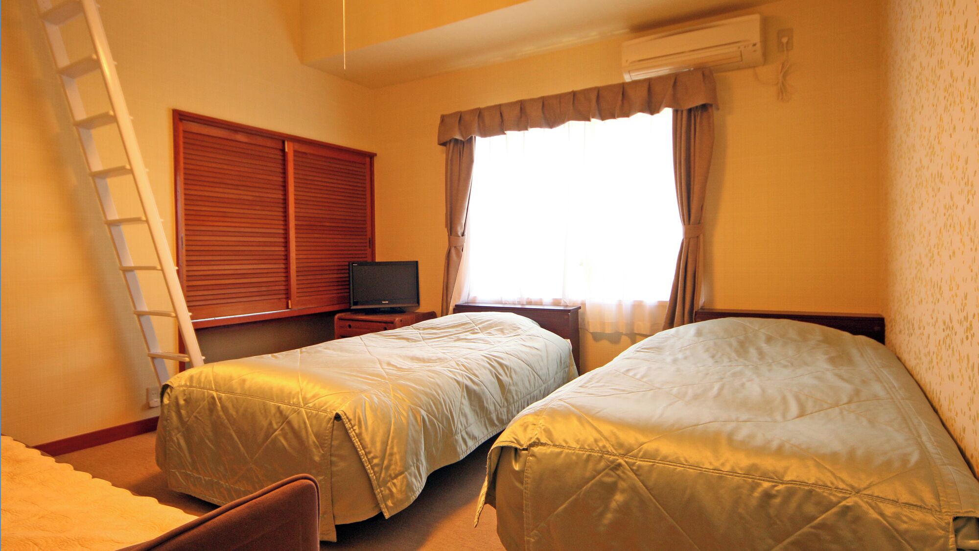 A hotel room with two beds, a TV, a ladder, and a window with curtains.