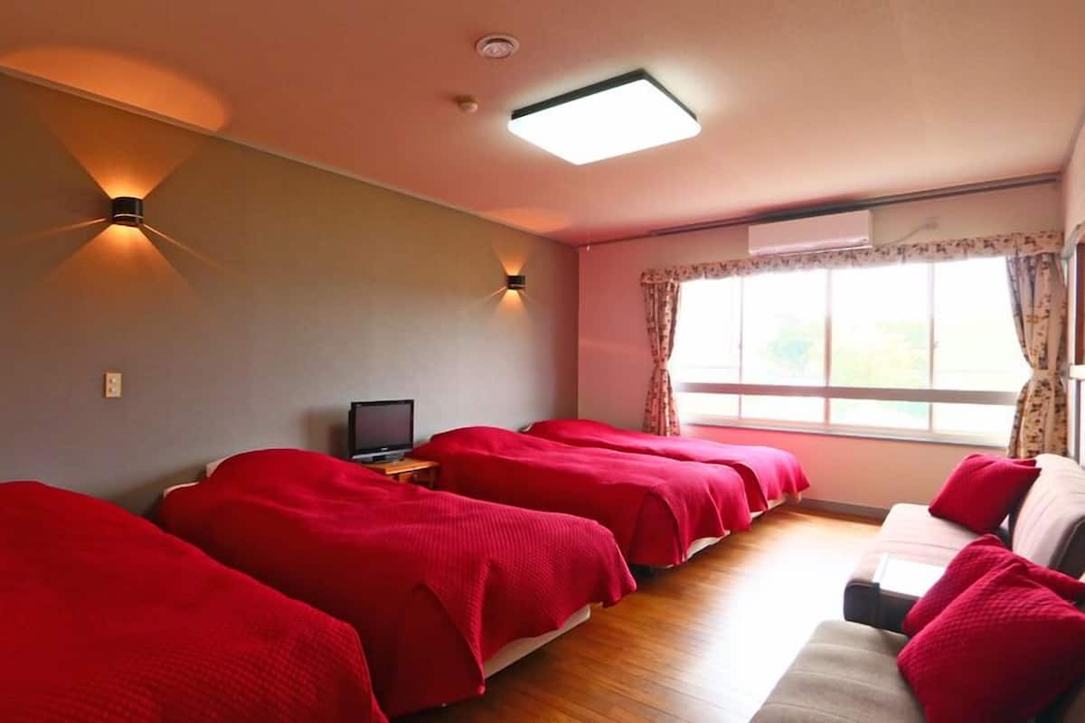 Ein Hotelzimmer mit zwei Betten, einem Fernseher und einem Fenster mit Vorhängen.