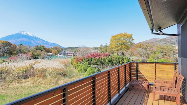 Una terraza de madera con vista a una montaña y follaje otoñal.
