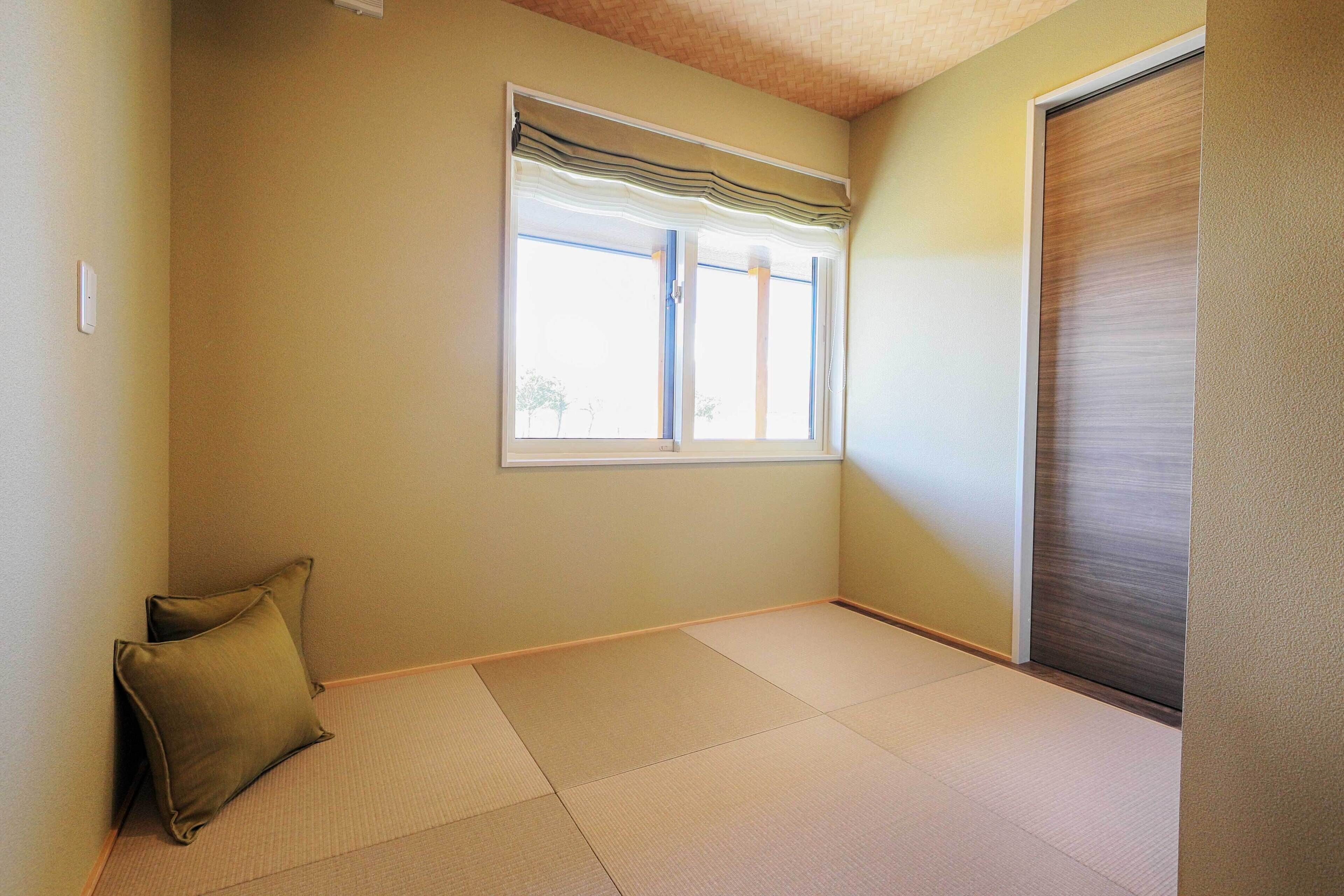 A room with tatami flooring, a sliding door, and a window with a valance.