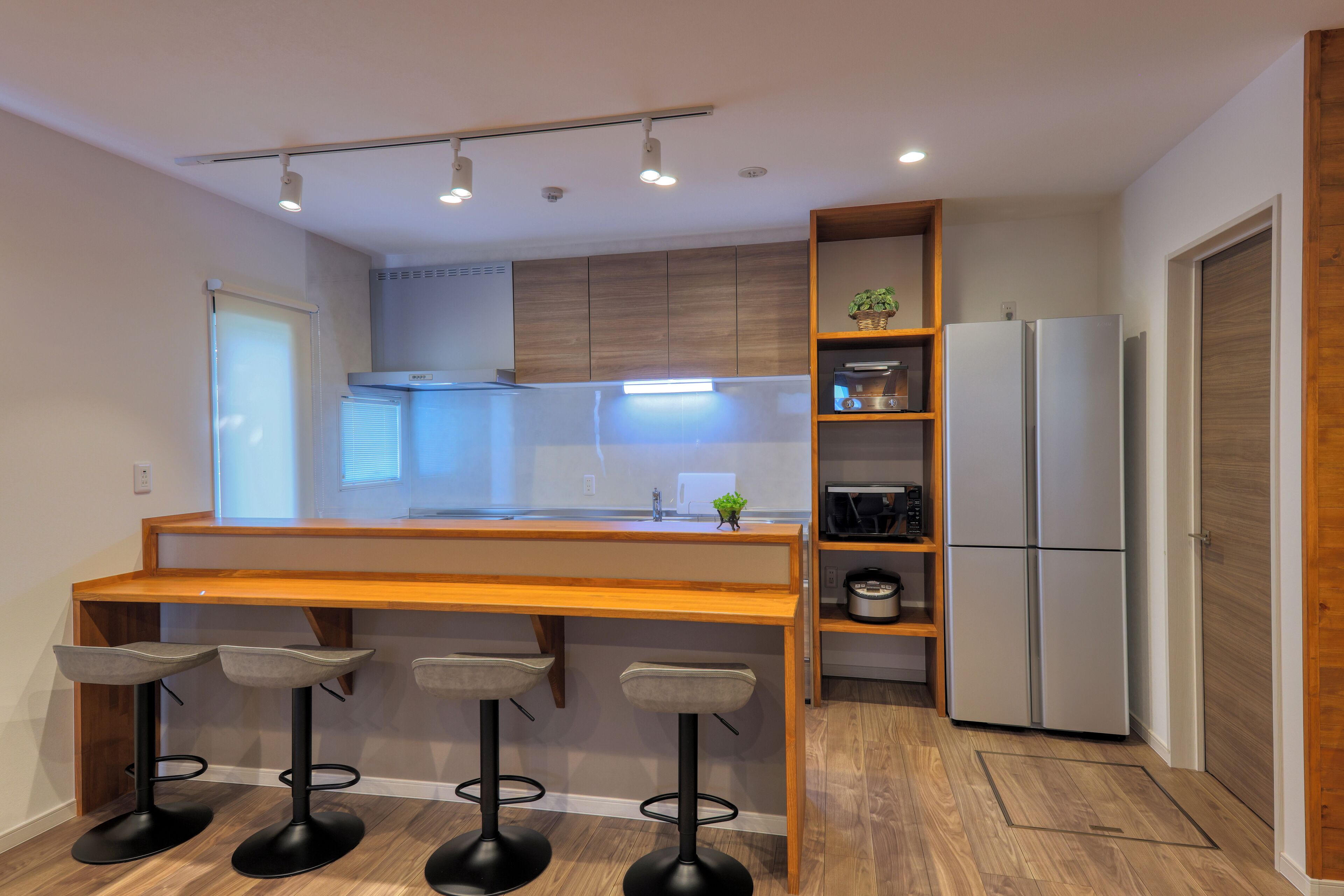 Una cocina moderna con una isla de madera, taburetes de bar, horno empotrado y refrigerador.