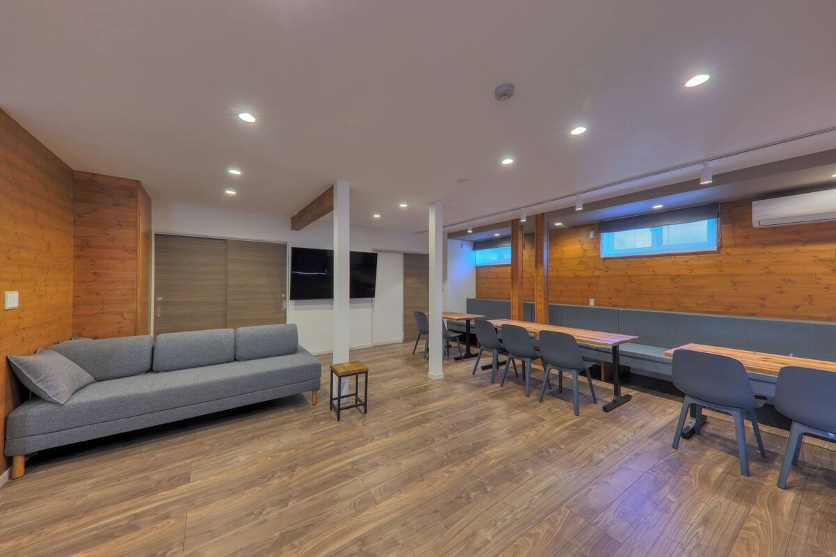 A modern conference room with a wooden accent wall, a grey sofa, and a long table with chairs.