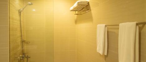 Ducha con cerramiento de vidrio, cabezal de ducha manual y grifo empotrado.