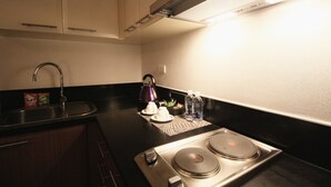 A kitchen with a stove, sink, and cabinets. - MaxStays Max Home at The Venice Residences (Taguig)