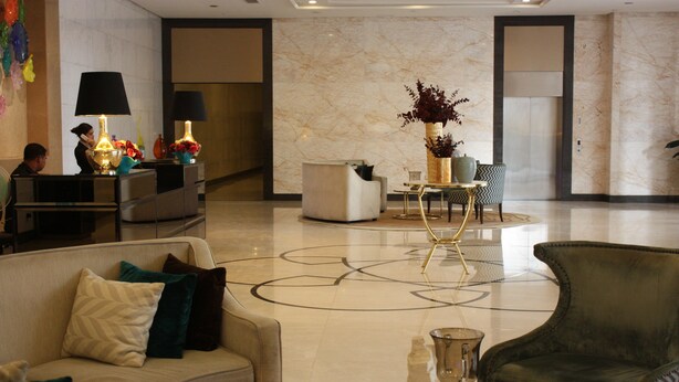 A lobby with a reception desk, seating area, and a decorative vase with flowers. - MaxStays Max Home at The Venice Residences (Taguig)