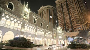 A hotel with a grand facade featuring arched windows and intricate patterns, surrounded by high-rise buildings. - MaxStays Max Home at The Venice Residences (Taguig)