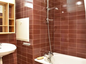 Une salle de bain avec une baignoire blanche, une douche dotée d’un robinet chromé et un lavabo blanc.