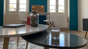 Una habitació amb una taula rodona, un bocal amb una planta, un got de llet i un quadern.