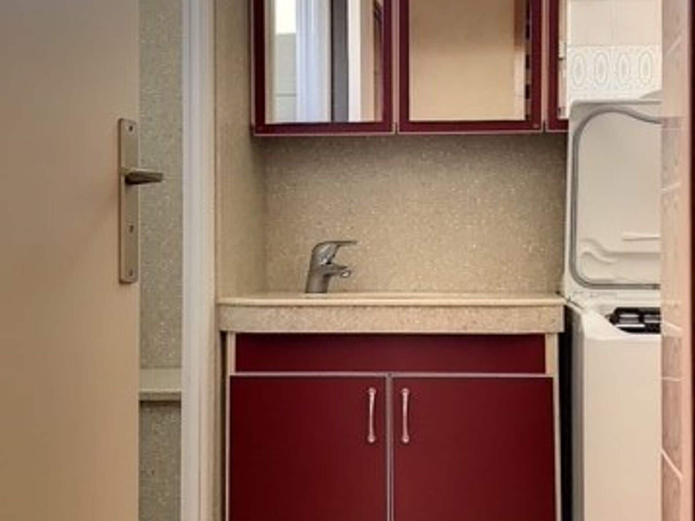 Une cuisine de taille réduite, équipée d’un évier, d’un petit plan de travail et d’un appareil électroménager blanc.