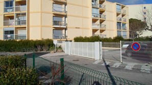 Un immeuble résidentiel à plusieurs étages, doté de balcons, d’une entrée sécurisée et d’un panneau indiquant qu’il est interdit de se garer.