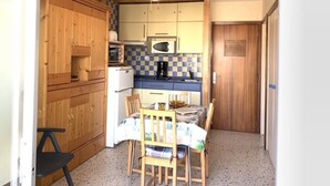 Une cuisine compacte dotée de meubles en bois, d’un four à micro-ondes, d’un réfrigérateur et d’une table à manger avec des chaises.