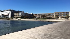Ein Hotel direkt am Wasser mit modernem Design, inklusive Poolbereich und einer Holzpromenade.