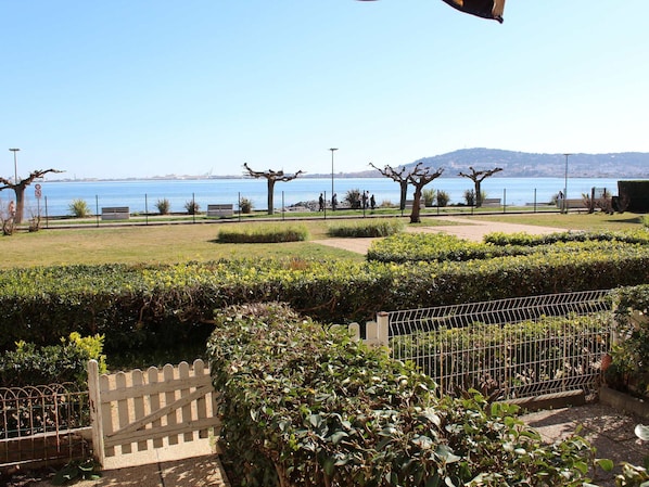 A park with a view of the sea, a fence, and a bench.