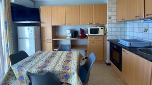 Une cuisine compacte dotée de meubles en bois, d’un four à micro-ondes, d’un réfrigérateur et d’un coin repas avec une table et des chaises.