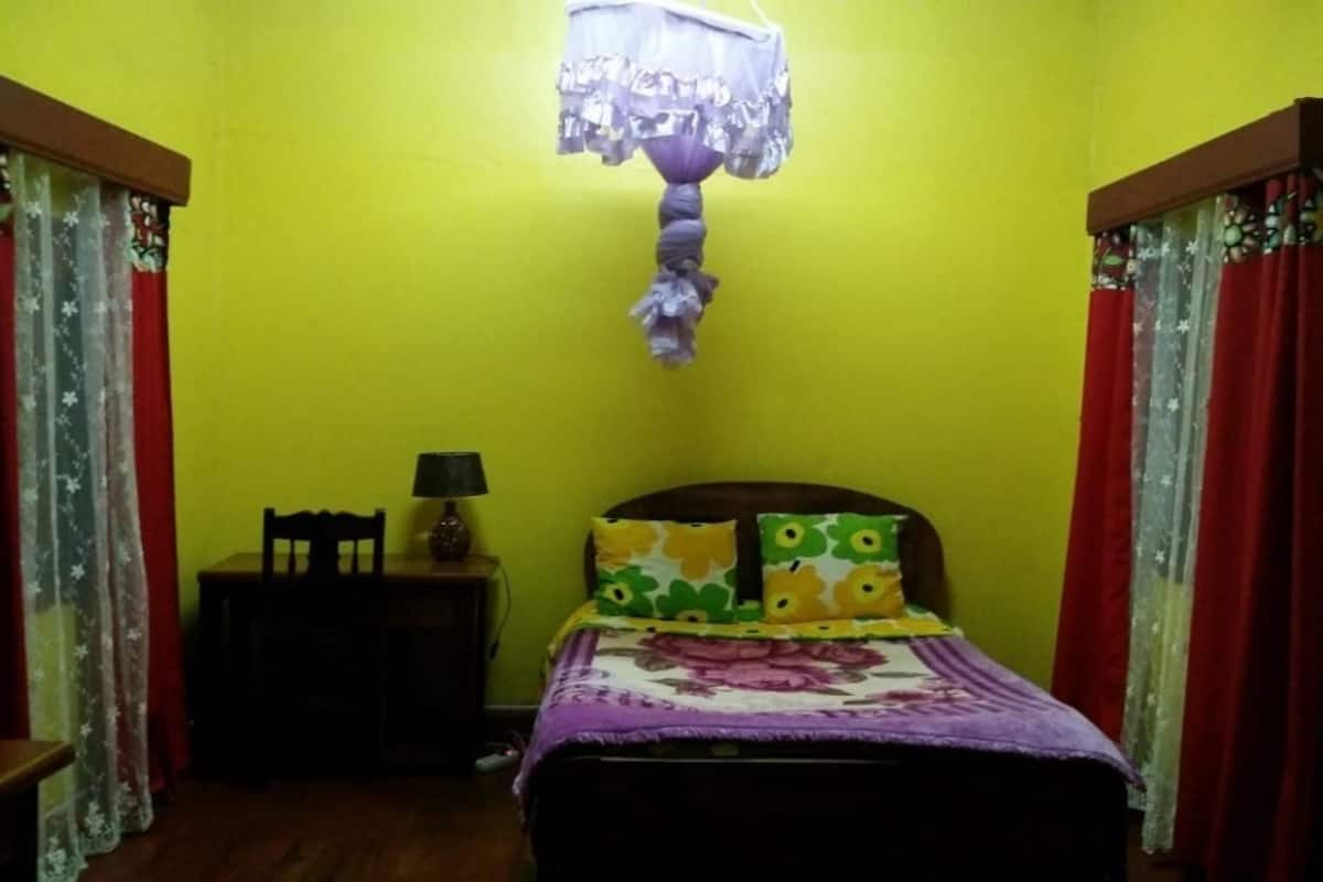 Une chambre avec un lit, une table de chevet, une lampe et des rideaux.