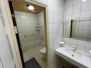 A small, tiled bathroom with a shower, toilet, and sink. - Lvyou B&B (Tianwei)