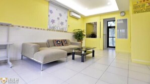 A bright yellow room with a sofa, a coffee table, and a potted plant. - Lvyou B&B (Tianwei)