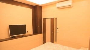 A bedroom with a bed, a television on a stand, a wardrobe, and an air conditioning unit. - Lvyou B&B (Tianwei)