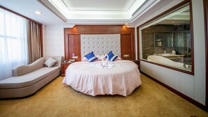 A well-appointed bedroom with a large bed, a sofa, a bathroom with a large mirror, and a ceiling with recessed lighting. - Xiaoxiang Binhu Hotel Yongzhou (Yongzhou)