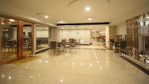 A spacious lobby with a polished marble floor, a reception area with a counter, and a seating area with tables and chairs. - Xiaoxiang Binhu Hotel Yongzhou (Yongzhou)