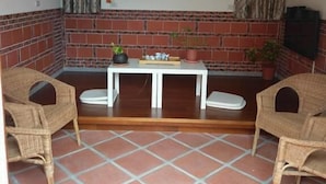 A small, enclosed patio area with a tiled floor, a brick wall, a table with chairs, and a ceiling fan. - Joylin 3 Homestay (Jinning)