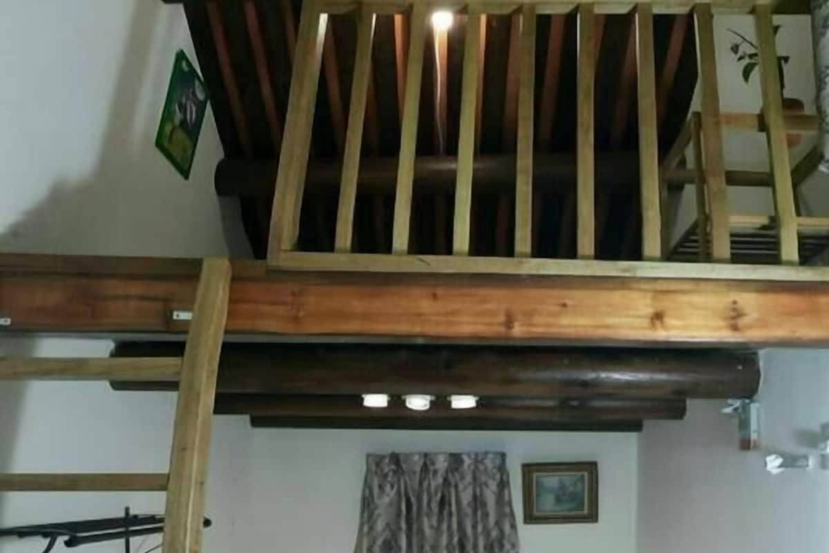 A compact room with a bunk bed, a small desk, a chair, and a TV.