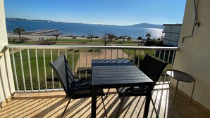 Een balkon met een tafel en stoelen met uitzicht op het water.