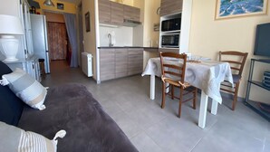 Um espaço compacto com cozinha compacta, área de refeições e sofá.