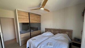 A bedroom with a bed, a ceiling fan, and a wardrobe.