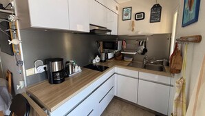 A compact kitchen with white cabinets, a microwave, a coffee maker, and a sink.