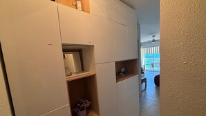 A hallway with built-in storage units, a potted plant, and a view of an outdoor balcony.