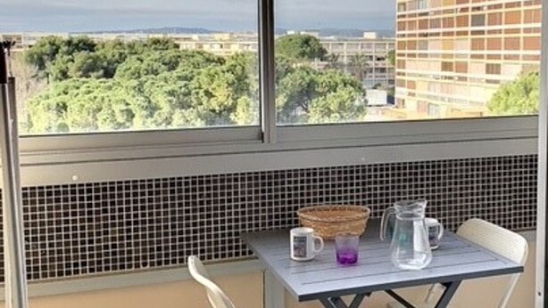 A balcony with a table, chairs, and a view of buildings and trees. - Charming air-conditioned studio, pets welcome in Balaruc-les-Bains (Balaruc-les-Bains)