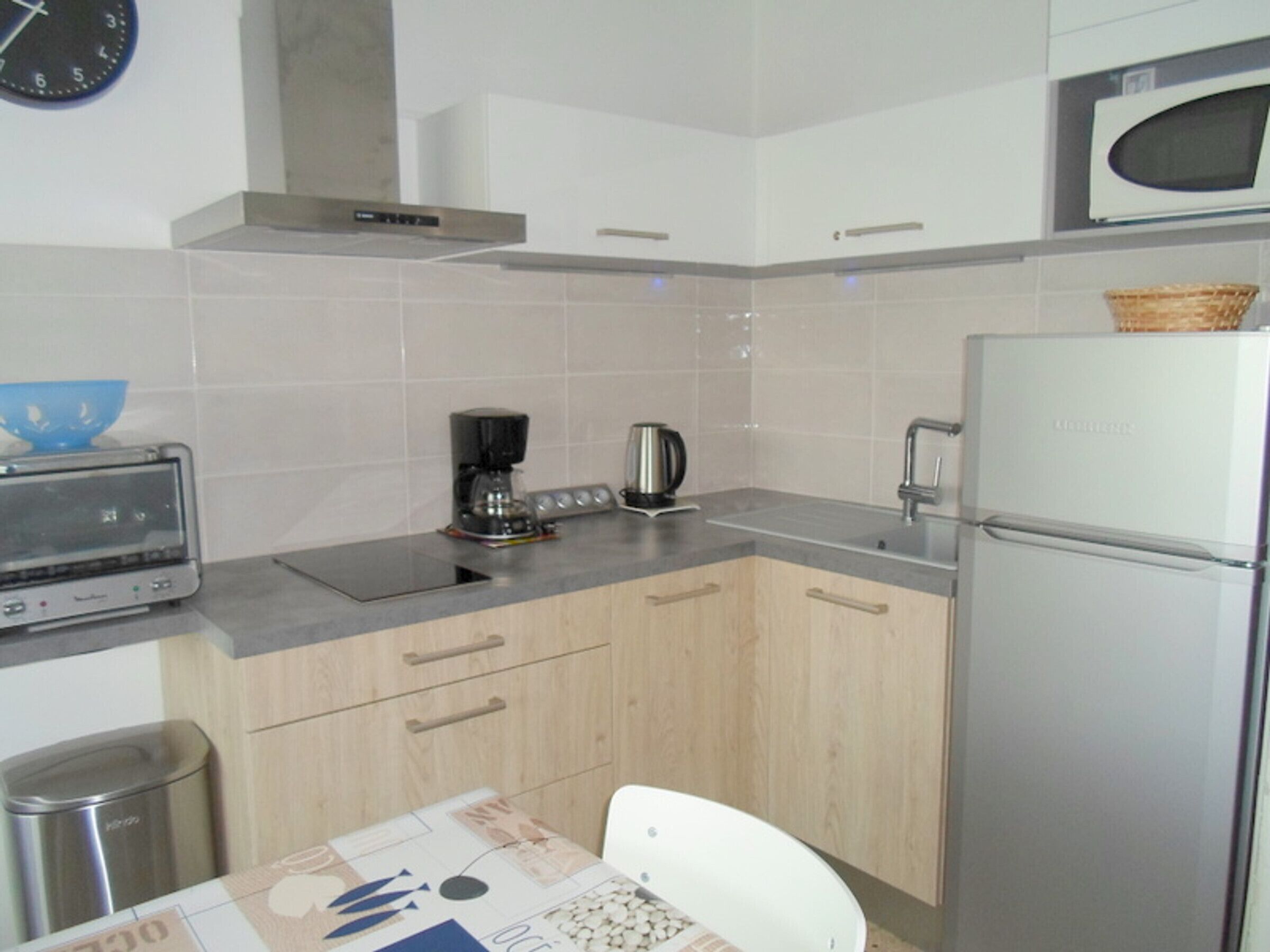 A modern kitchen with a microwave, toaster, coffee maker, and a refrigerator.