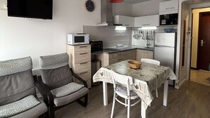 A compact kitchen with a microwave, toaster, and refrigerator. There is a dining table with chairs and a hanging light fixture. - Charming air-conditioned studio, pets welcome in Balaruc-les-Bains (Balaruc-les-Bains)