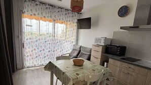 A compact kitchen with a dining table, chairs, a microwave, and a TV. - Charming air-conditioned studio, pets welcome in Balaruc-les-Bains (Balaruc-les-Bains)