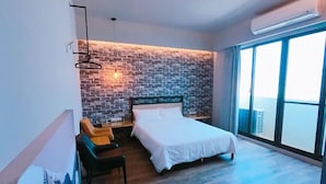 Una habitación de hotel moderna con pared de ladrillo, una cama grande, un escritorio y una silla.