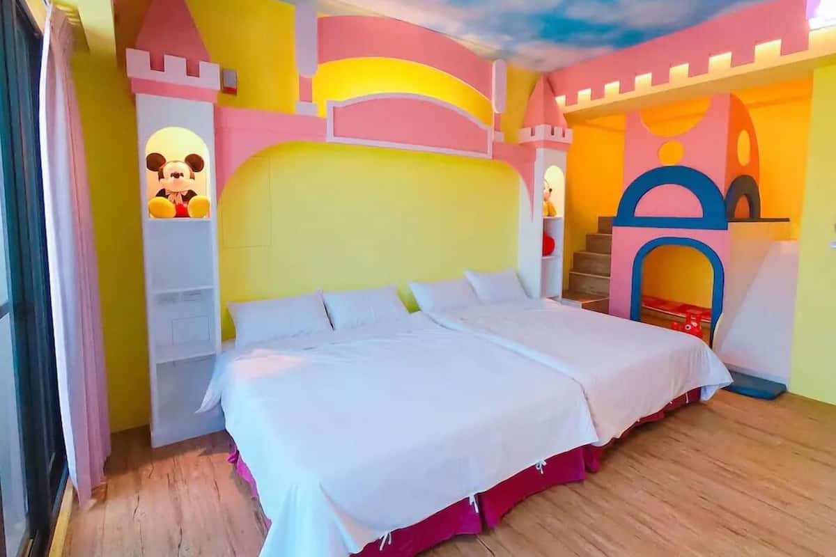 A bedroom with a large bed, a castle-themed wall, and a Mickey Mouse decoration.