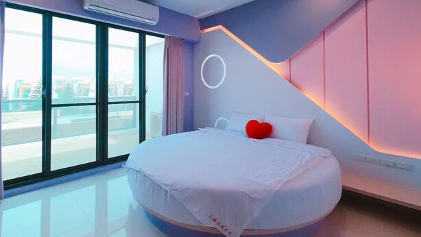 Un dormitorio moderno con una cama grande, vistas a través de un amplio ventanal e iluminación circular en el techo.