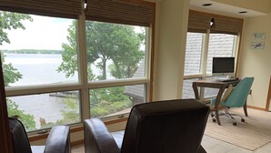A room with large windows overlooking a lake, a desk with a computer, and two chairs. - Waterfront home with dock!




 (Afton)