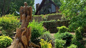 A garden with a wooden sculpture, various shrubs, and a stone wall. - Waterfront home with dock!




 (Afton)
