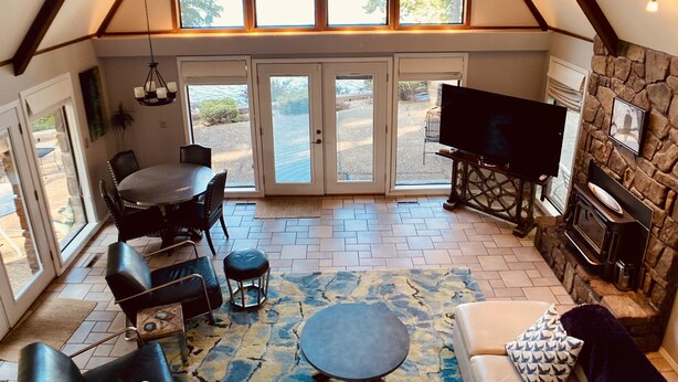 A cozy living room with a stone fireplace, a large TV, and a dining area with a table and chairs. - Waterfront home with dock!




 (Afton)