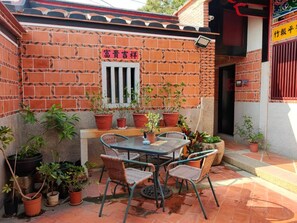 A patio area with a brick wall, a small window, and potted plants. - Joylin Inn (Jinhu)