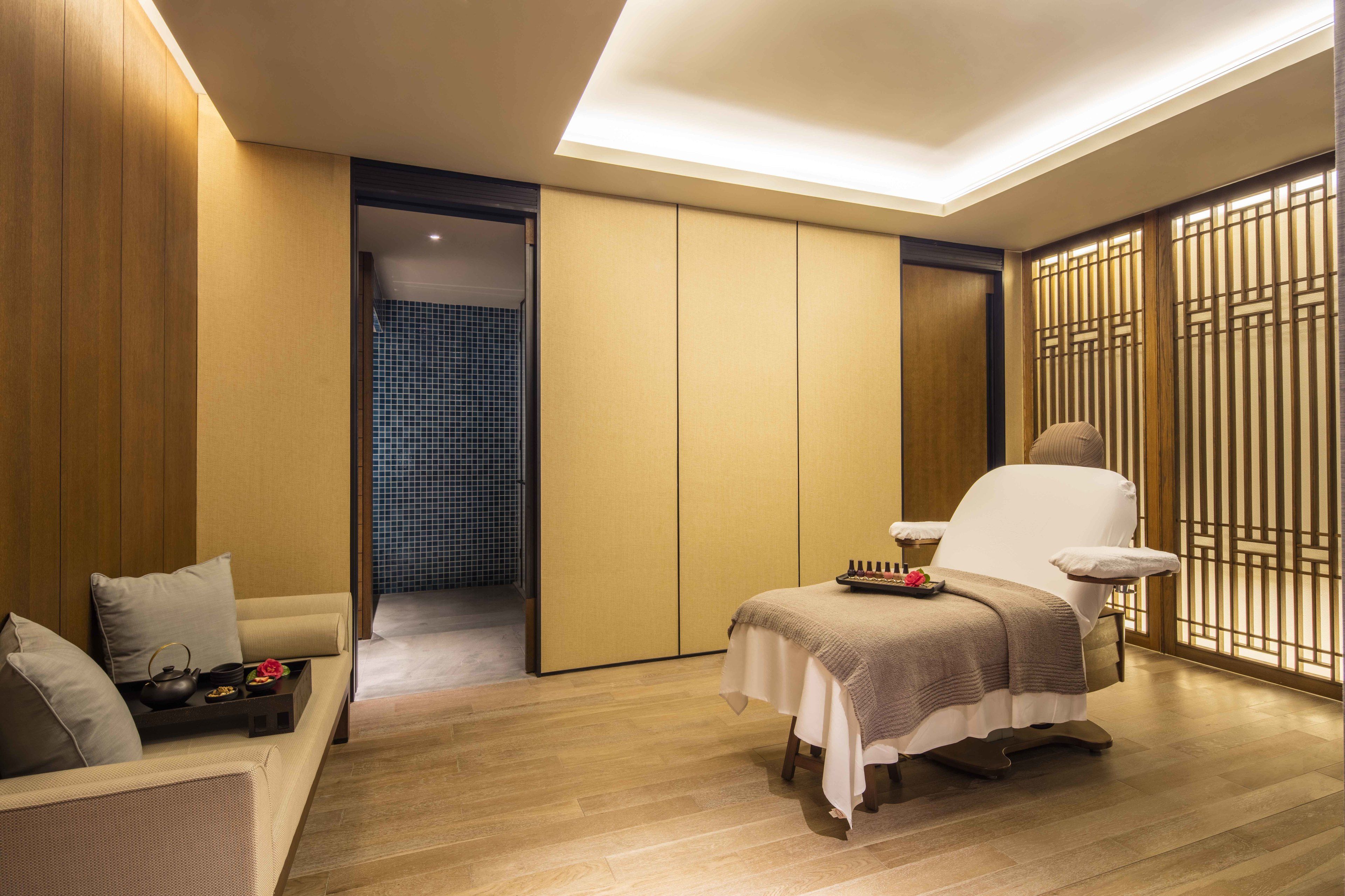 Een moderne kamer met een bank, een massagestoel en een klein tafeltje met dienblad.
