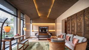 A modern living room with a sofa, a wooden bench, and a table with a lamp. - Ahn Luh Zhujiajiao (Shanghai)
