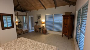 A cozy room with a bed, a wooden cabinet, wicker furniture, and a desk with a lamp. - Oceanfront Luxury. Spectacular Sunsets and Mountain View. HHI Featured. Avalon. (Old Town)