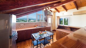 A kitchen with wooden beams, a dining table set for four, and a view of the outdoors.