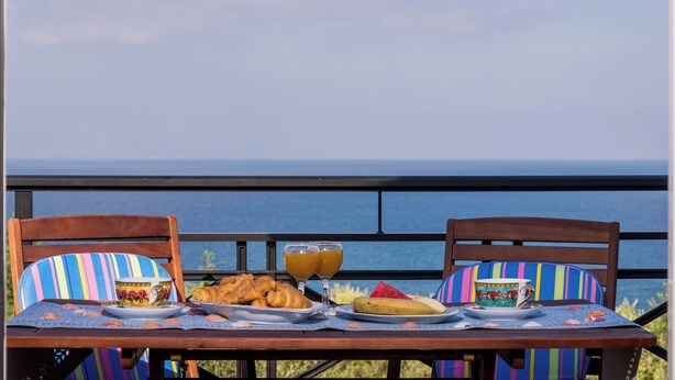 A dining table with breakfast items and a view of the ocean.