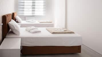 Ein minimalistisch eingerichtetes Hotelzimmer mit zwei Betten, weißen Leinentüchern und ordentlich gefalteten Handtüchern.