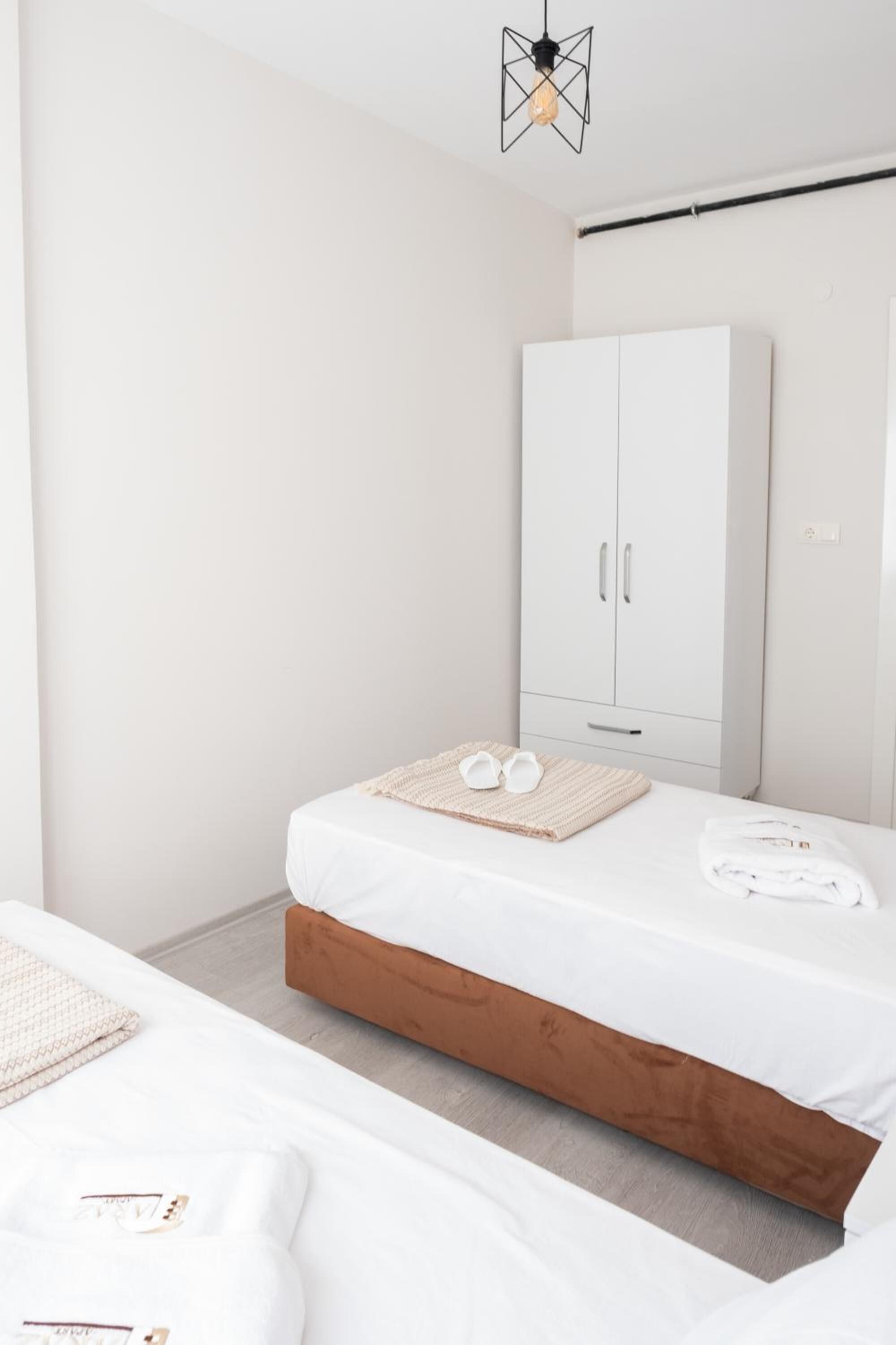 A bedroom with a bed, a wardrobe, and a hanging light fixture.